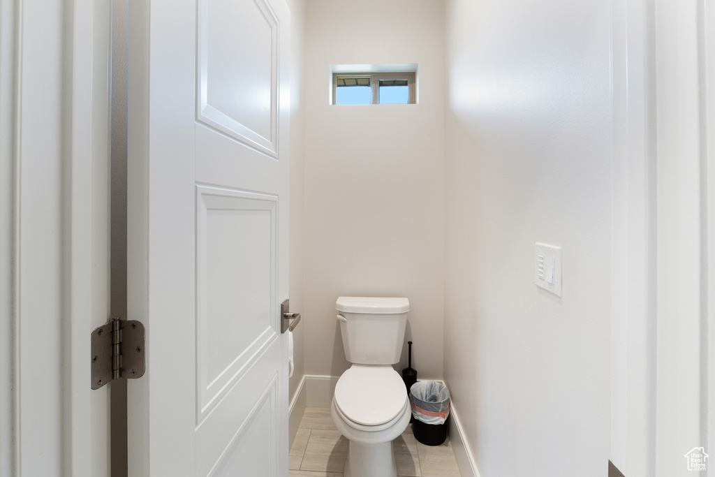 Bathroom featuring wood finished floors, baseboards, and toilet