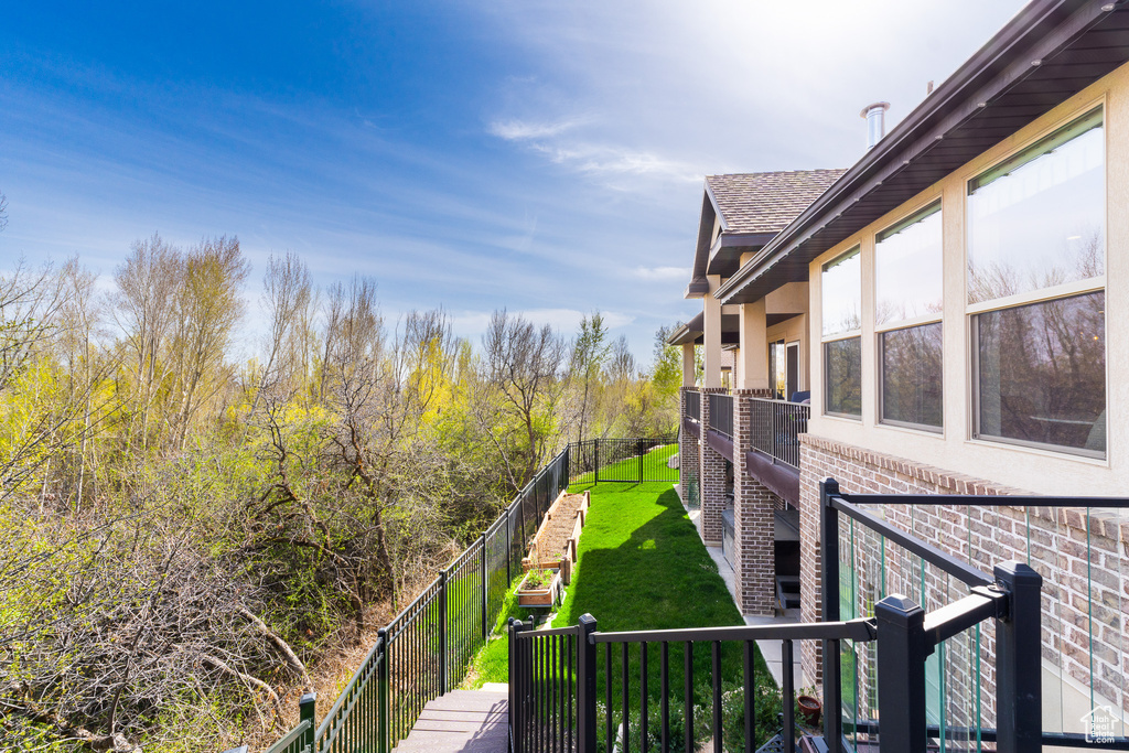 Exterior space with fence, a shingled roof, stucco siding, a lawn, and brick siding