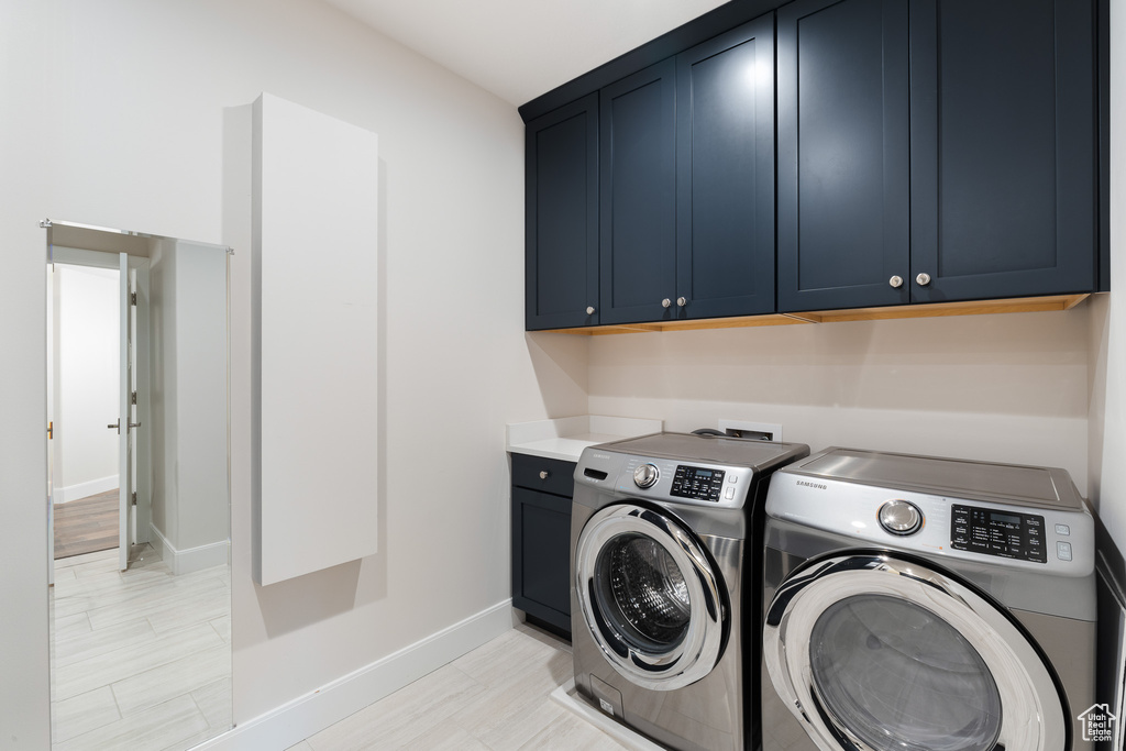 Clothes washing area featuring washer and dryer, baseboards, and cabinet space