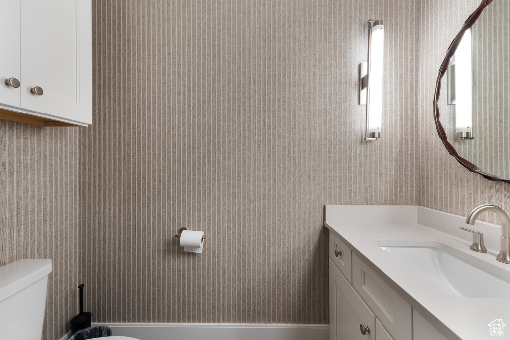 Bathroom with wallpapered walls, toilet, and vanity