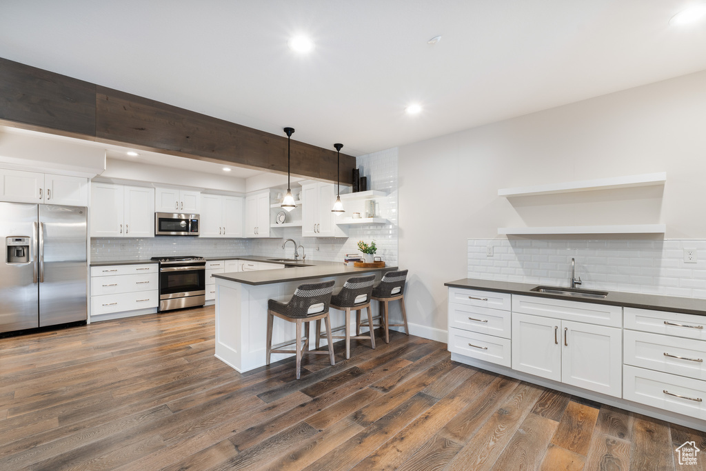 Kitchen featuring dark countertops, appliances with stainless steel finishes, open shelves, and a sink