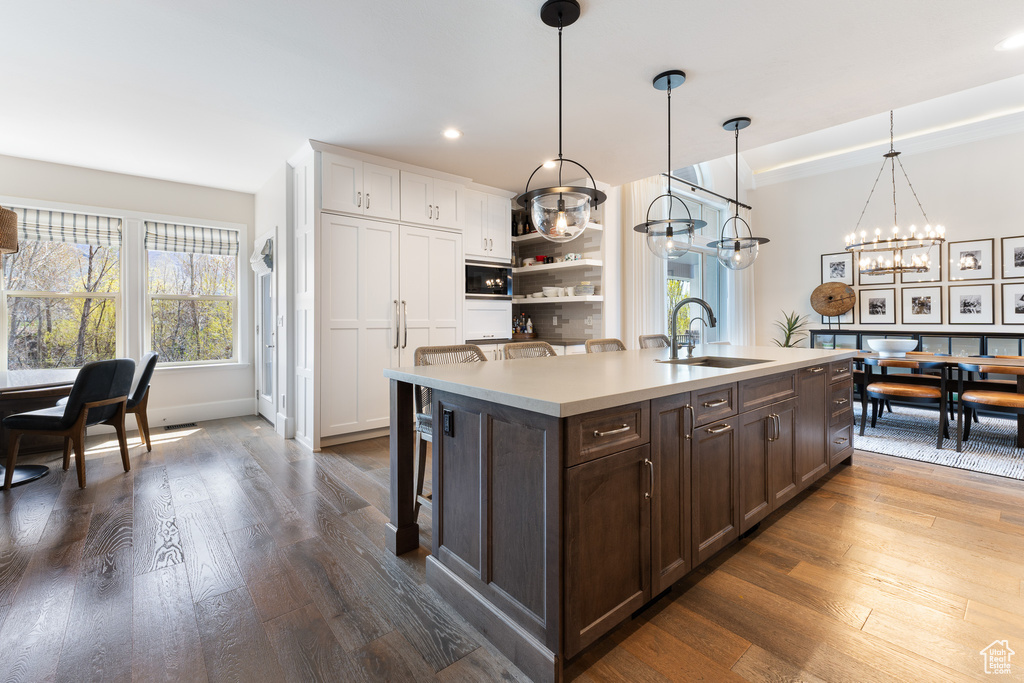Kitchen with dark brown cabinets, a sink, light countertops, dark wood-type flooring, and recessed lighting