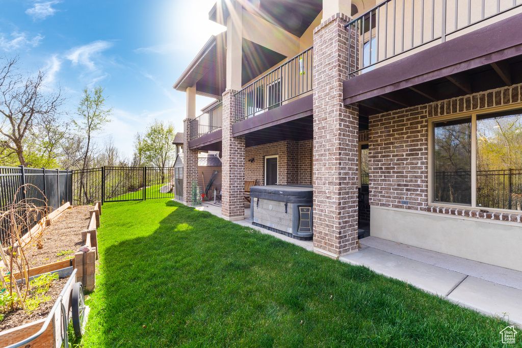 View of yard featuring a garden, a hot tub, a fenced backyard, and a balcony