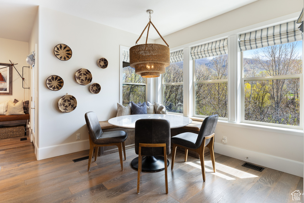 Dining space with wood finished floors, visible vents, baseboards, and a healthy amount of sunlight