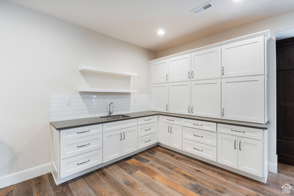 Kitchen with tasteful backsplash, dark countertops, open shelves, a sink, and visible vents