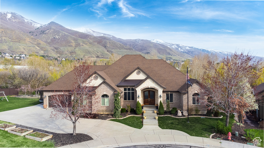 View of front of home with concrete driveway, a mountain view, a front yard, and brick siding