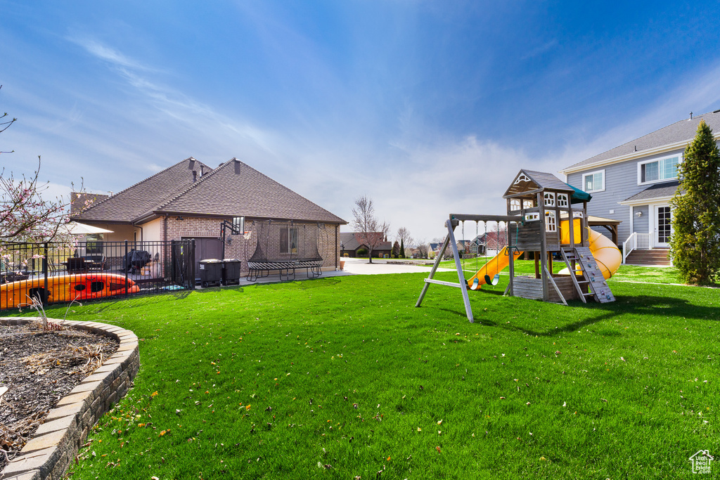 View of yard with a playground and fence