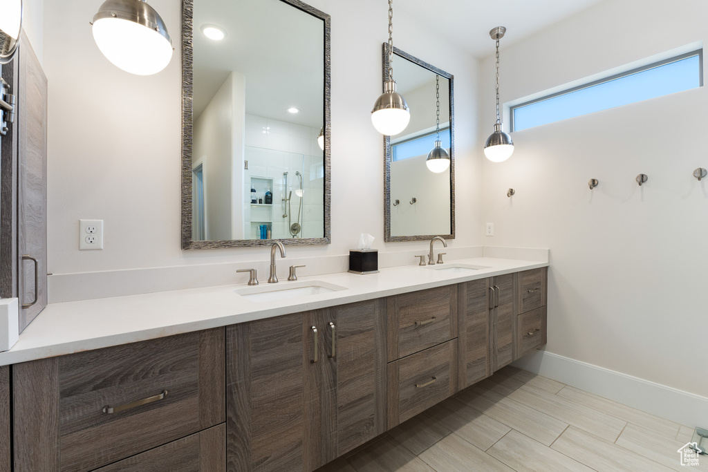 Bathroom featuring a shower with shower door, double vanity, and a sink