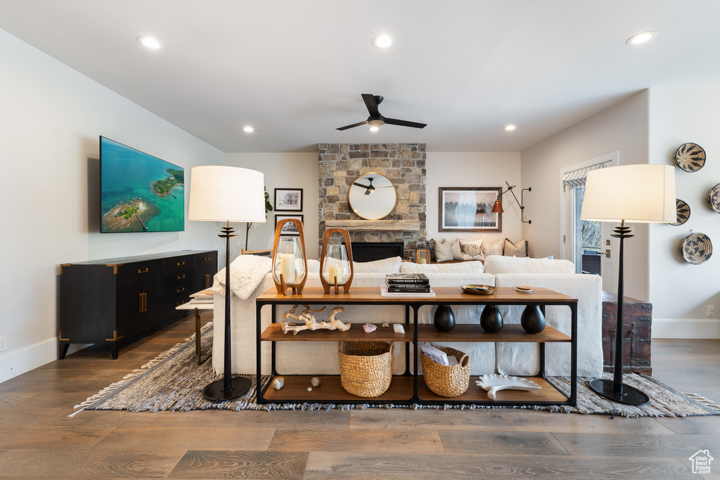 Living room with a fireplace, dark wood-style flooring, ceiling fan, and recessed lighting