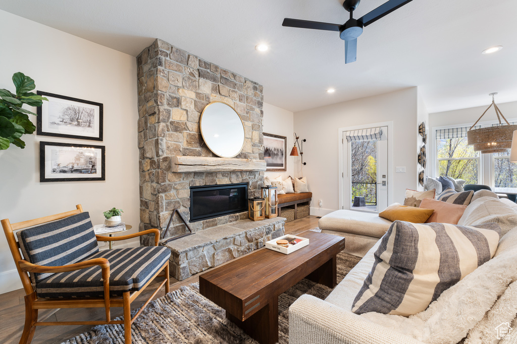 Living area featuring recessed lighting, a stone fireplace, wood finished floors, a ceiling fan, and baseboards