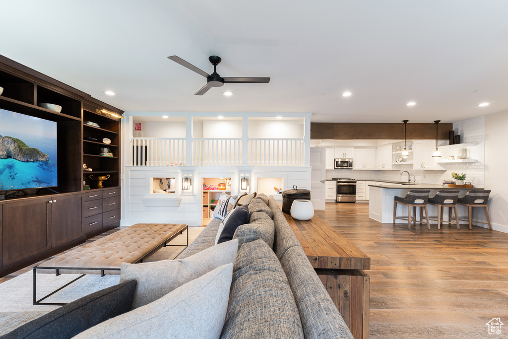 Living room featuring a ceiling fan, recessed lighting, and light wood-style flooring
