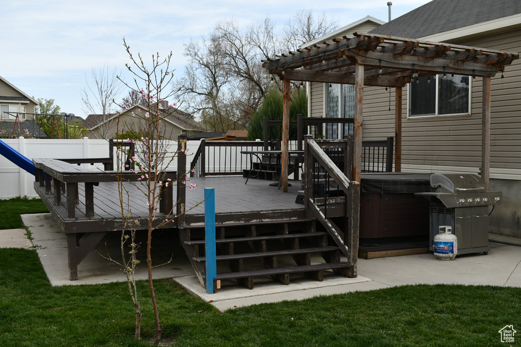 Wooden terrace featuring grilling area, a pergola, fence, and a hot tub