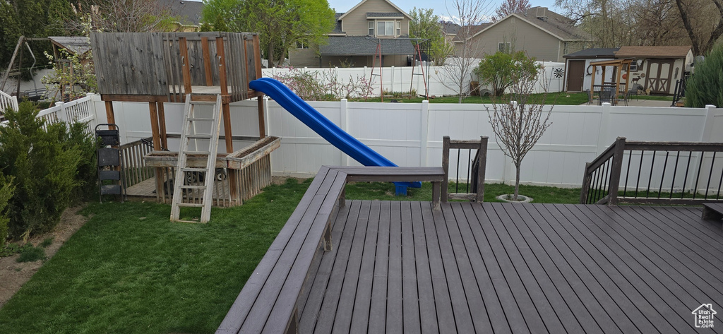 View of playground featuring a residential view, a fenced backyard, a deck, and a lawn