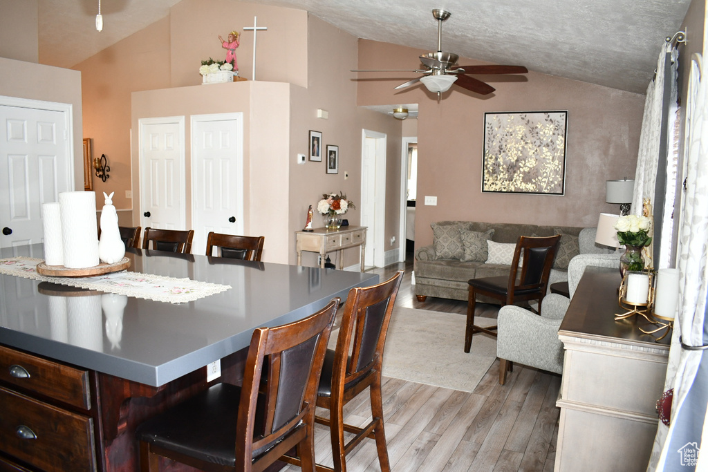 Dining space featuring light wood-style flooring, ceiling fan, and vaulted ceiling
