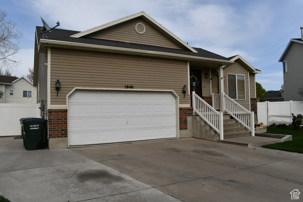 Ranch-style house featuring concrete driveway, brick siding, fence, and a garage