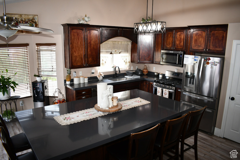 Kitchen featuring a sink, appliances with stainless steel finishes, a kitchen bar, and dark countertops
