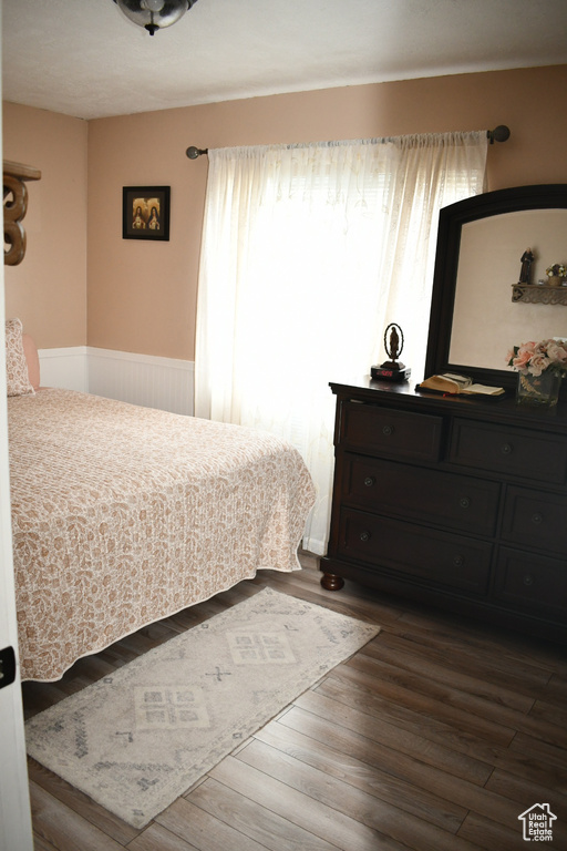Bedroom featuring dark wood-type flooring and a wainscoted wall