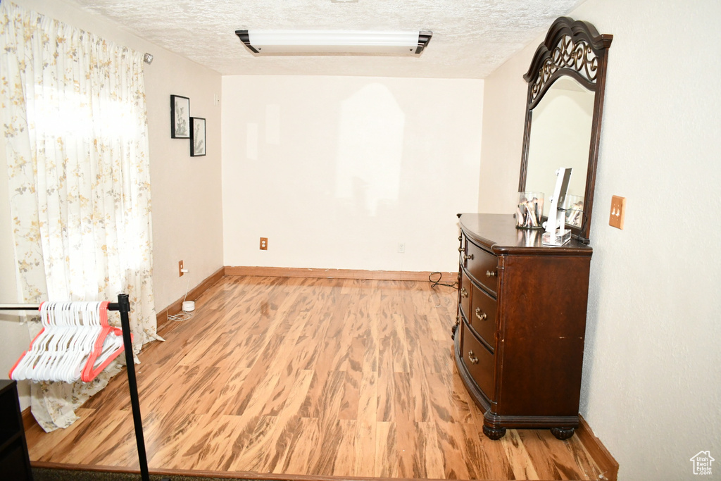 Spare room featuring light wood-style floors, baseboards, and a textured ceiling