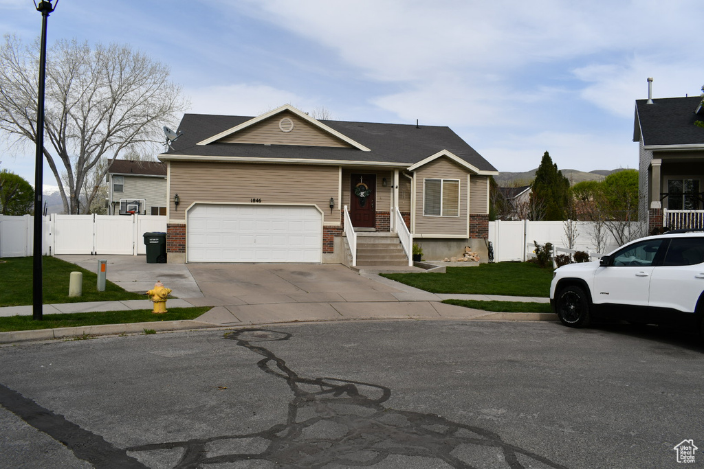 View of front of house featuring brick siding, a front yard, fence, and a gate
