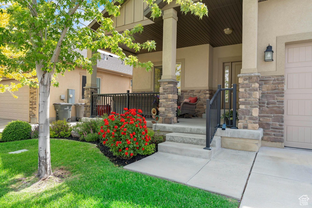 Property entrance with covered porch, stone siding, and stucco siding