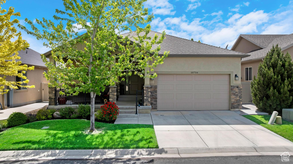 View of front of home featuring stucco siding, concrete driveway, an attached garage, and stone siding