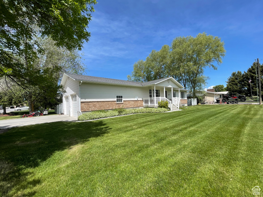 View of front of home featuring brick siding, a porch, a front lawn, concrete driveway, and an attached garage