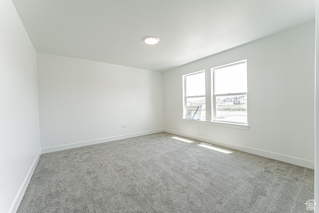 Carpeted empty room with baseboards and a textured ceiling
