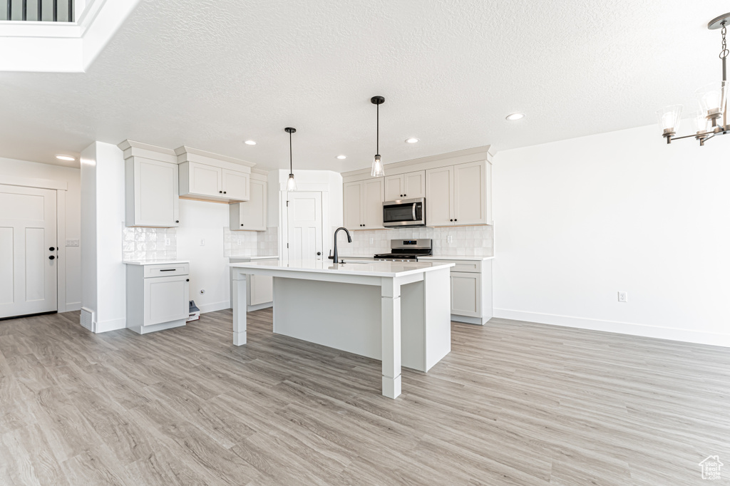 Kitchen featuring stainless steel appliances, a chandelier, tasteful backsplash, light countertops, and recessed lighting