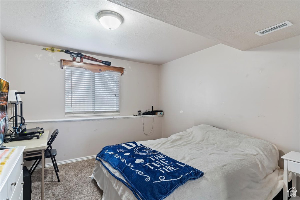 Bedroom featuring carpet, visible vents, baseboards, and a textured ceiling