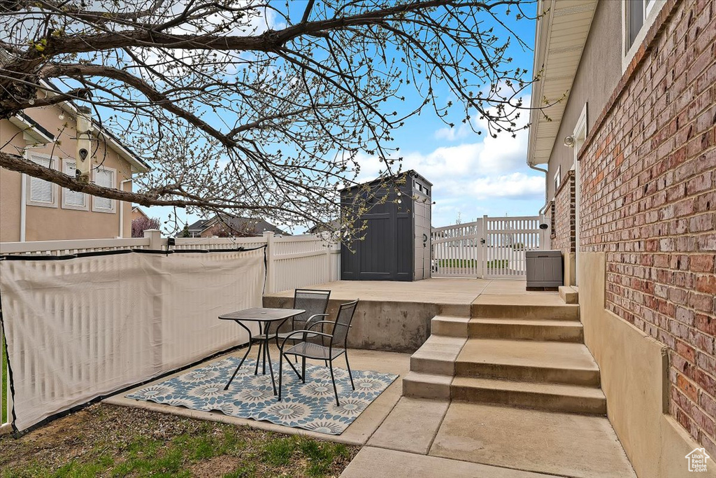 View of patio / terrace with an outbuilding, fence, a deck, and a storage unit