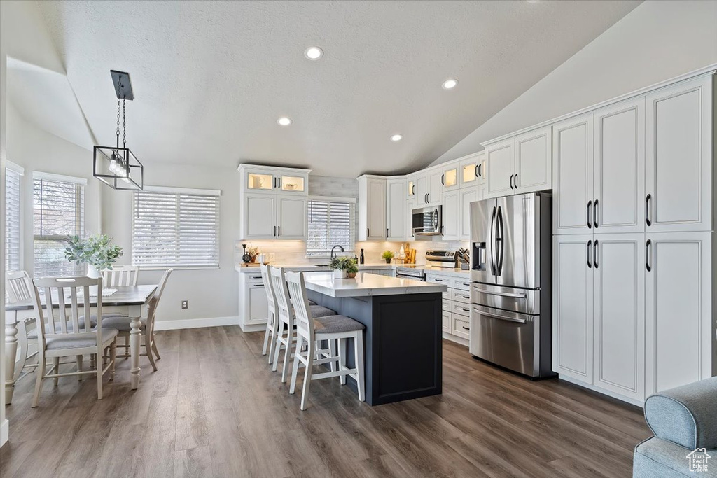 Kitchen featuring a kitchen island, light countertops, vaulted ceiling, and appliances with stainless steel finishes