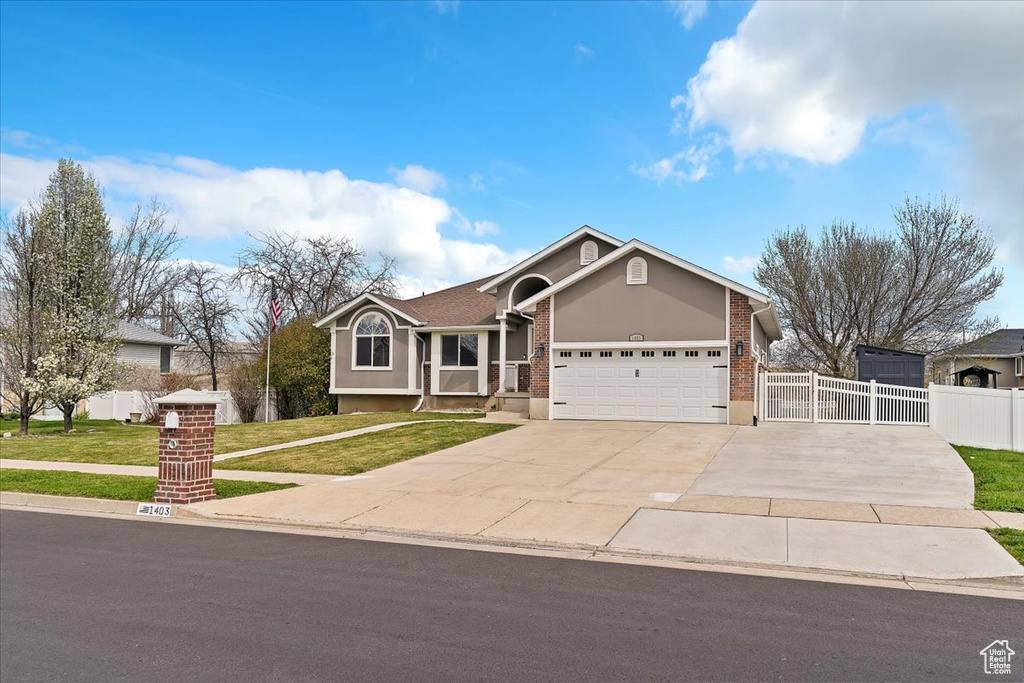 View of front of home featuring a garage, a front yard, fence, brick siding, and driveway