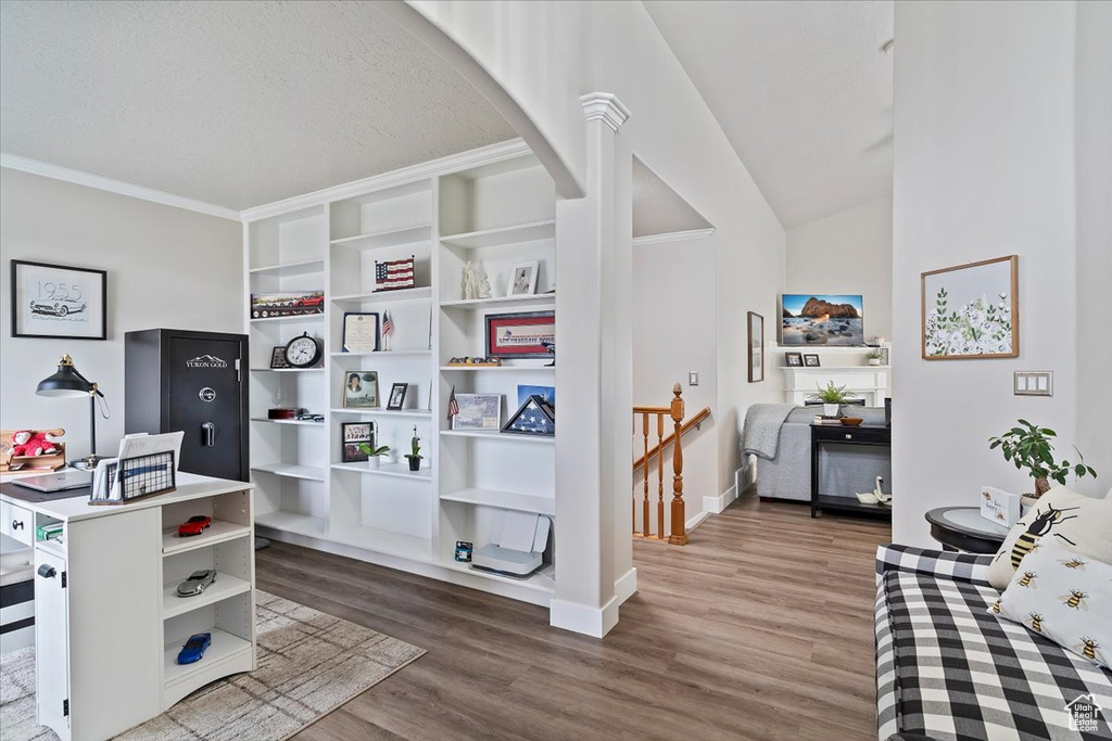 Office featuring arched walkways, baseboards, crown molding, and wood finished floors