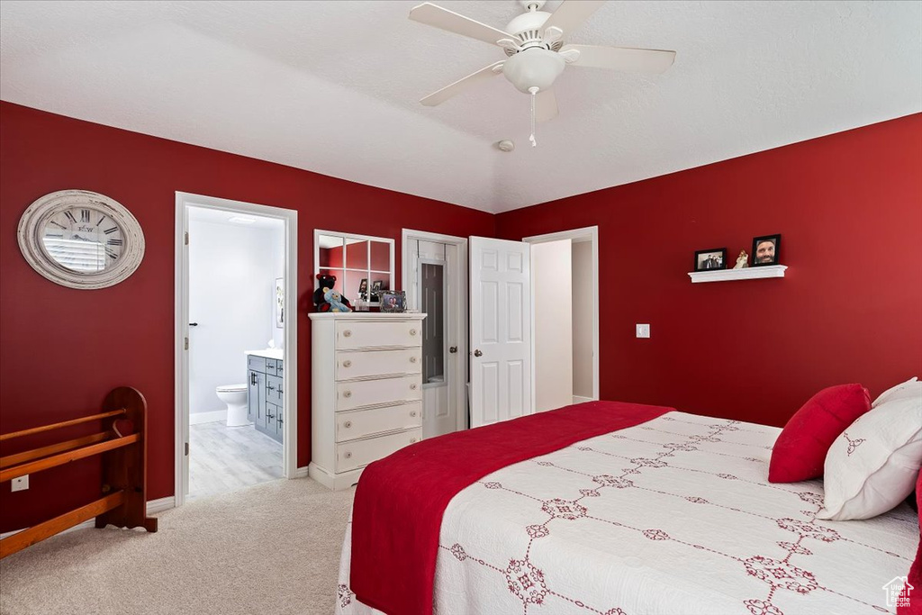 Bedroom with ensuite bathroom, baseboards, a ceiling fan, and carpet