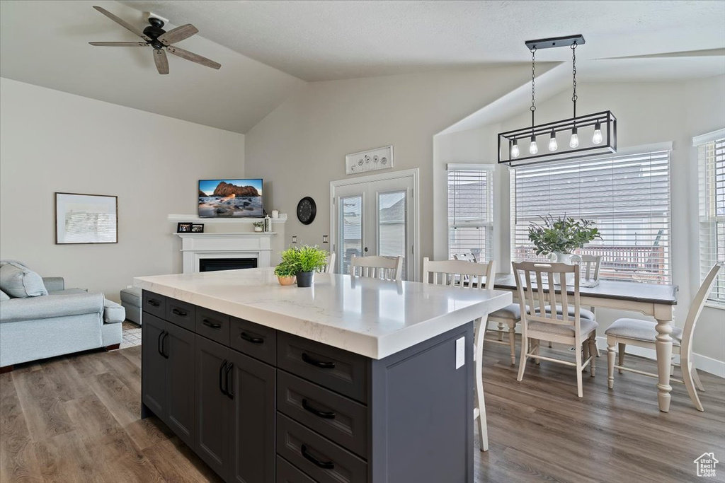 Kitchen featuring ceiling fan, vaulted ceiling, a center island, open floor plan, and dark wood-style floors