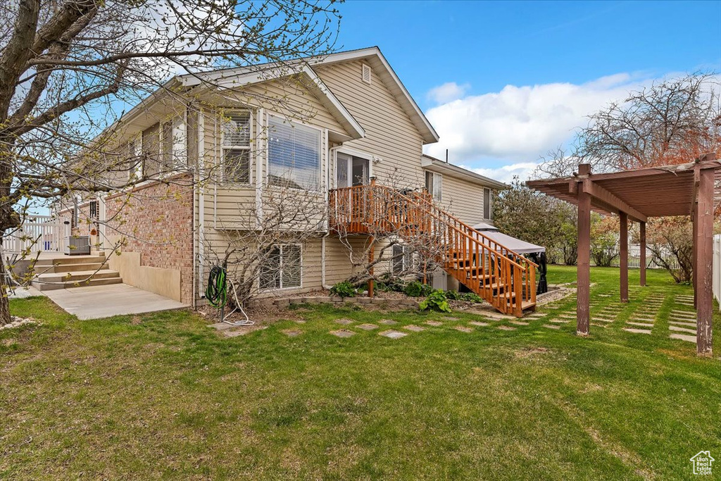 Back of property with stairway, cooling unit, and a lawn