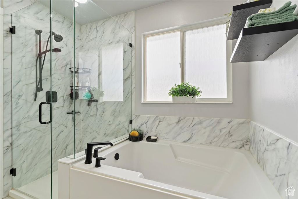 Bathroom with a bath, a marble finish shower, and a wealth of natural light