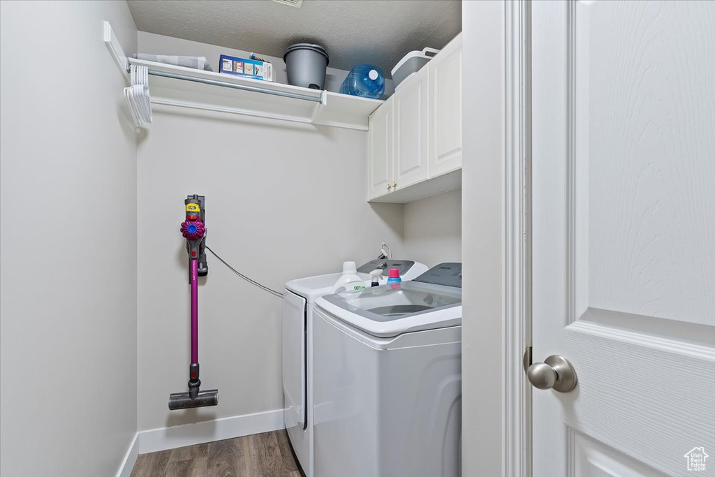 Laundry room featuring washer and dryer, dark wood-type flooring, baseboards, and cabinet space