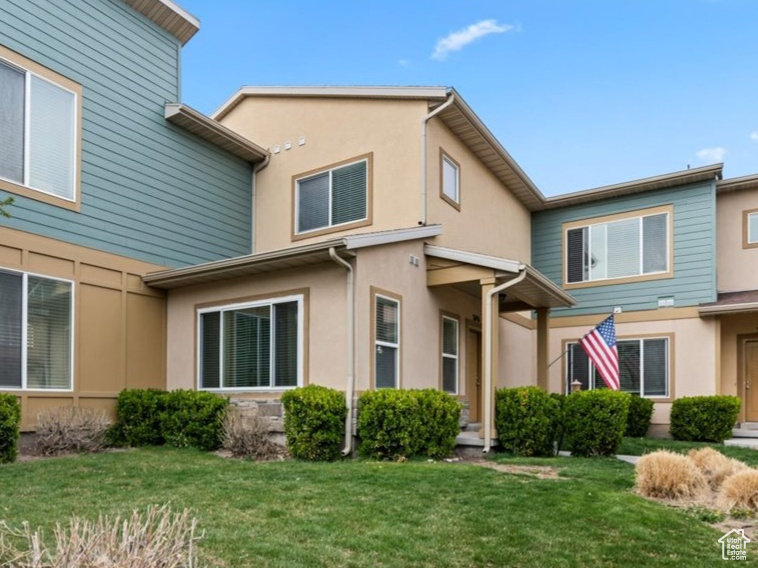 View of front of home with a front yard and stucco siding