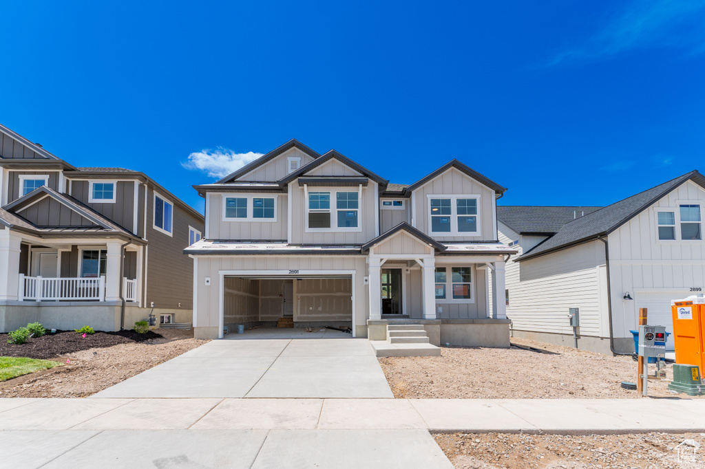 Craftsman-style home featuring covered porch, board and batten siding, concrete driveway, and a garage