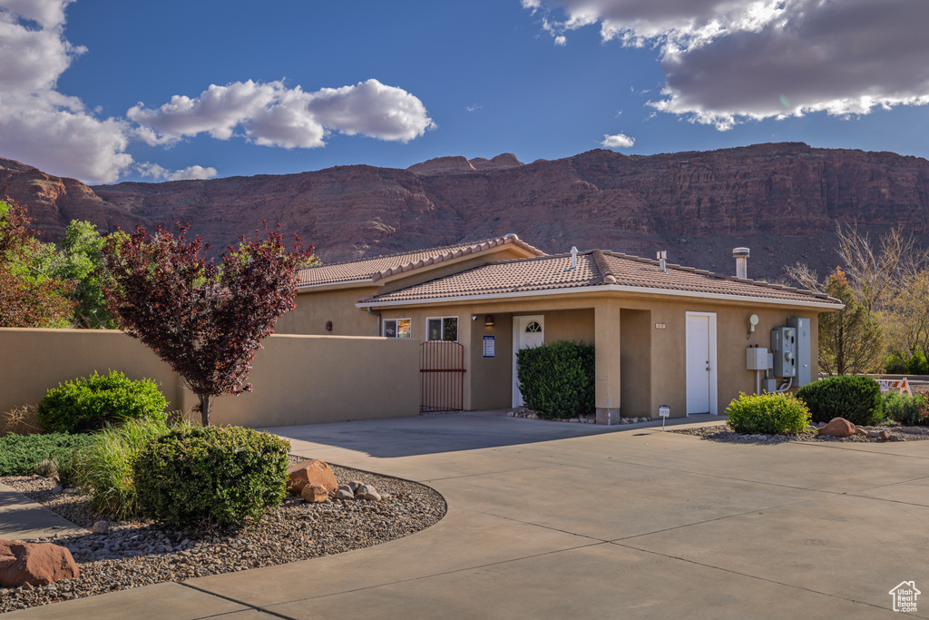 View of front of home with a tiled roof, fence, curved driveway, and stucco siding