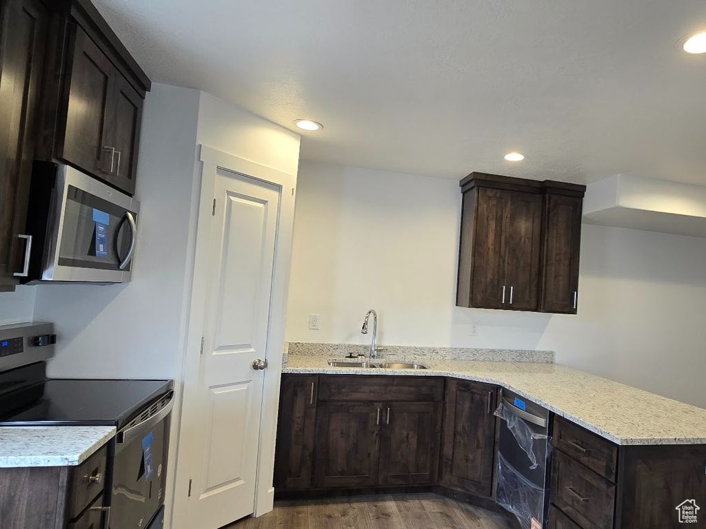 Kitchen with stainless steel appliances, a sink, dark wood-style floors, recessed lighting, and baseboards