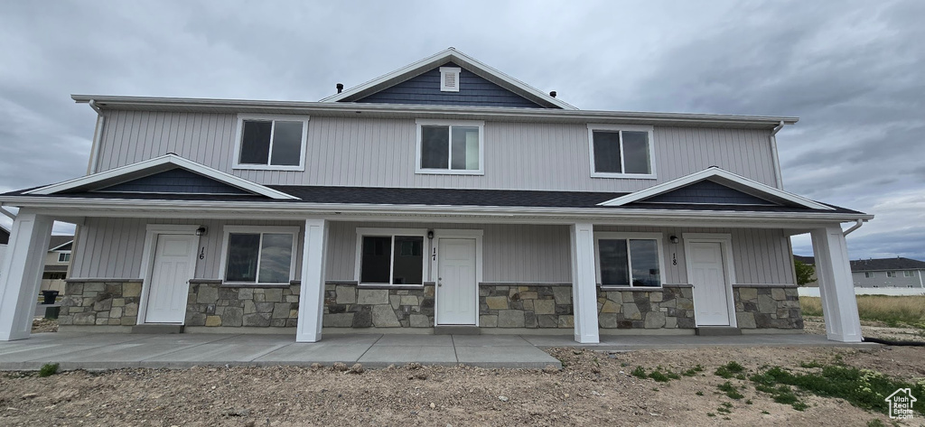 Back of property with a porch and stone siding