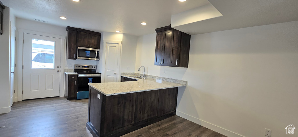 Kitchen with stainless steel microwave, electric range, baseboards, dark wood-style flooring, and dark brown cabinets