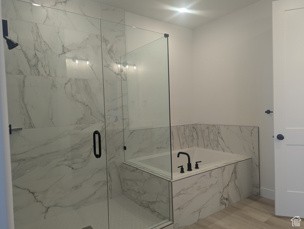 Bathroom with a garden tub, a marble finish shower, and wood finished floors