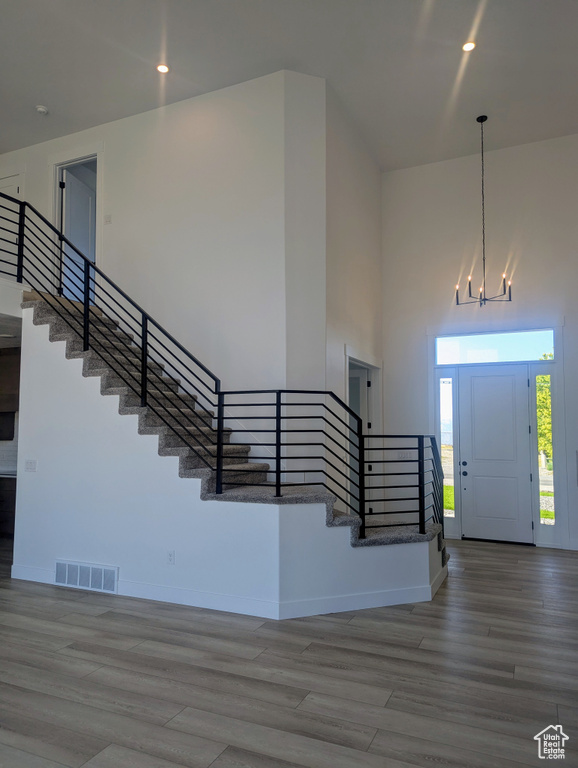 Foyer with stairway, wood finished floors, a high ceiling, recessed lighting, and a chandelier