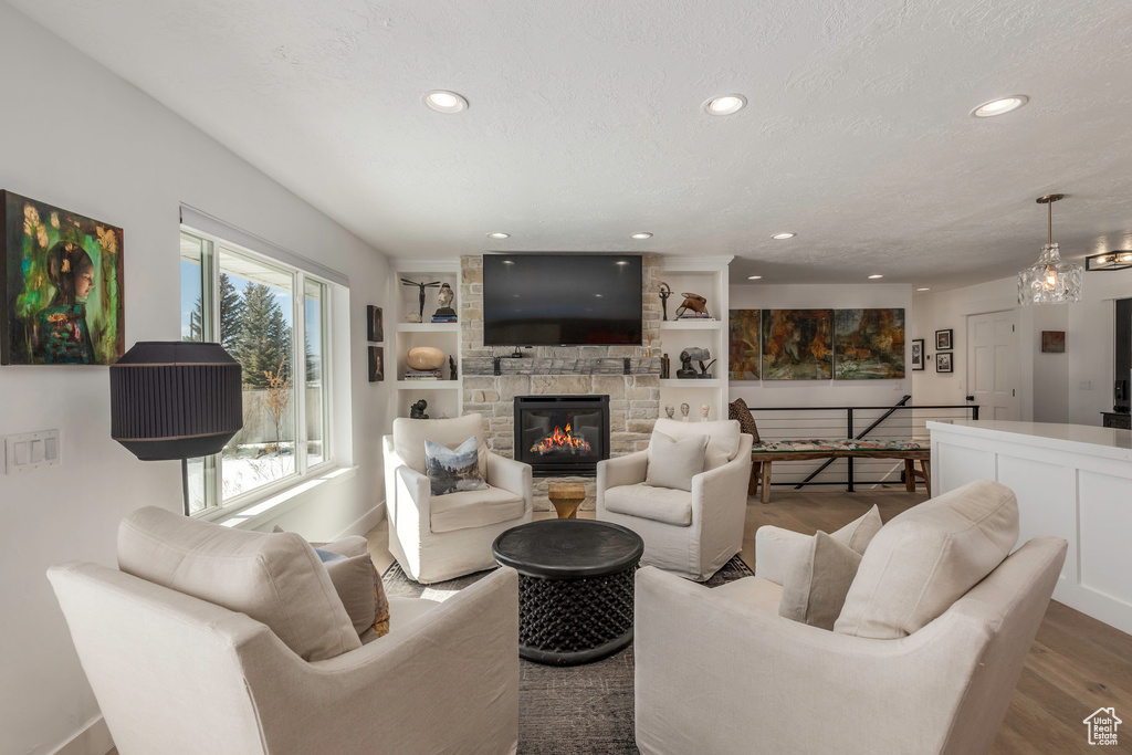Living area featuring recessed lighting, wood finished floors, a fireplace, baseboards, and built in shelves