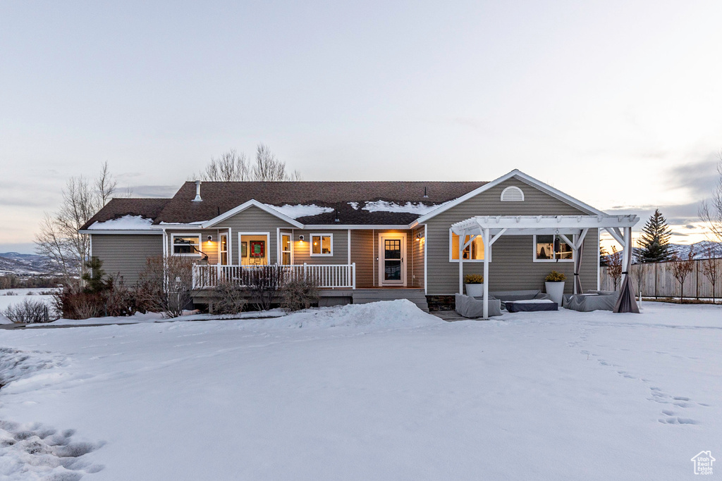 Single story home featuring a pergola and a wooden deck
