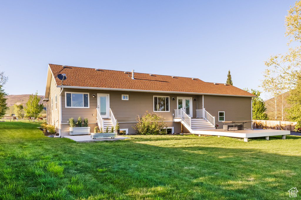 Back of house with a deck, a yard, and roof with shingles