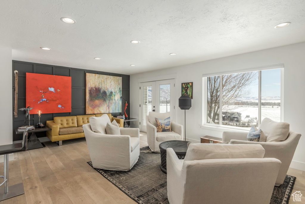 Living area featuring recessed lighting, light wood-type flooring, french doors, baseboards, and a textured ceiling